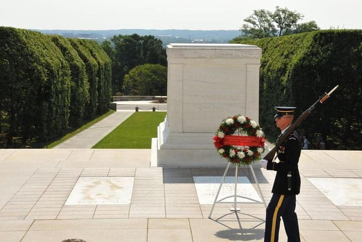 um homem uniformizado em frente a um memorial de guerra