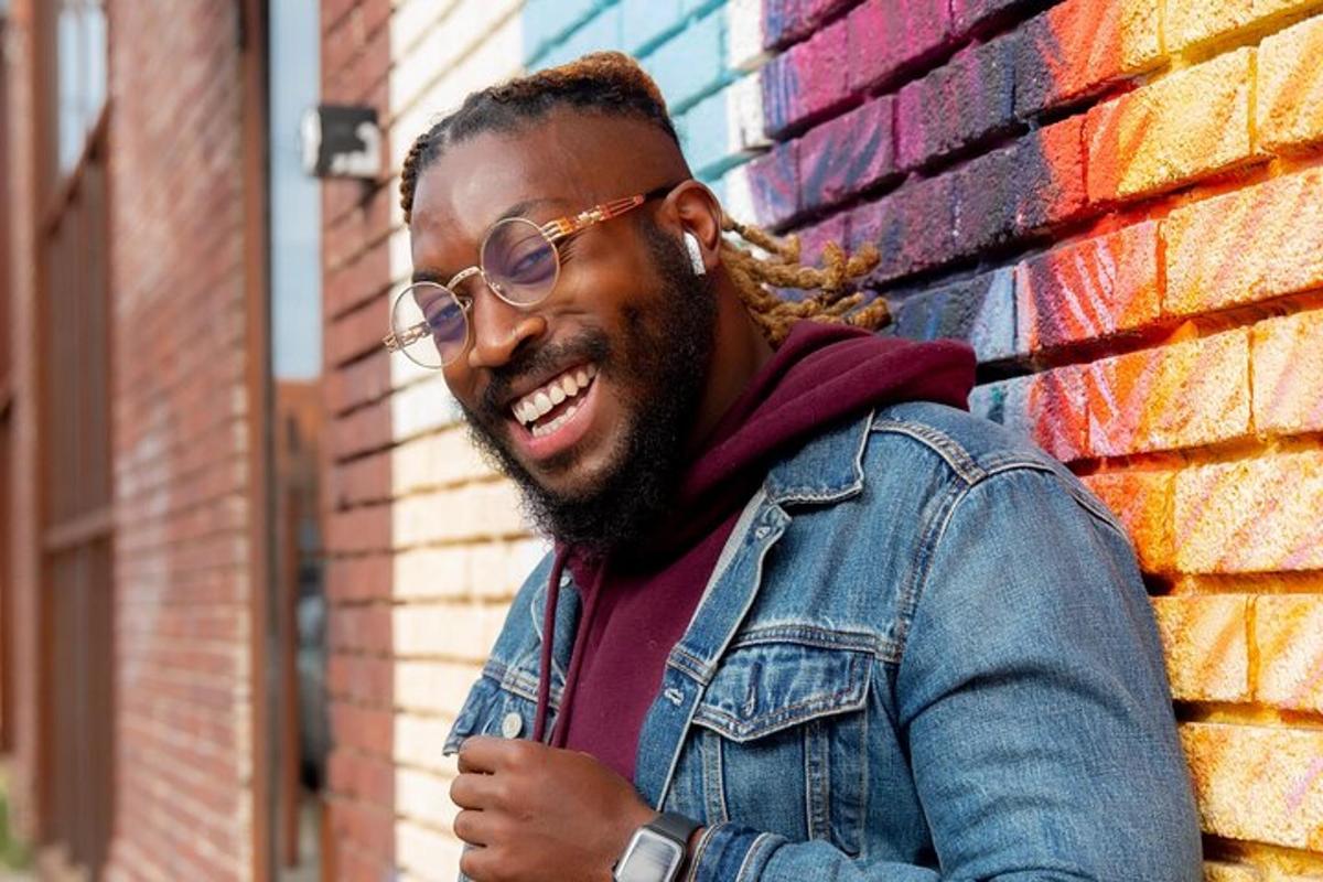 Un hombre con gafas de pie frente a una pared.