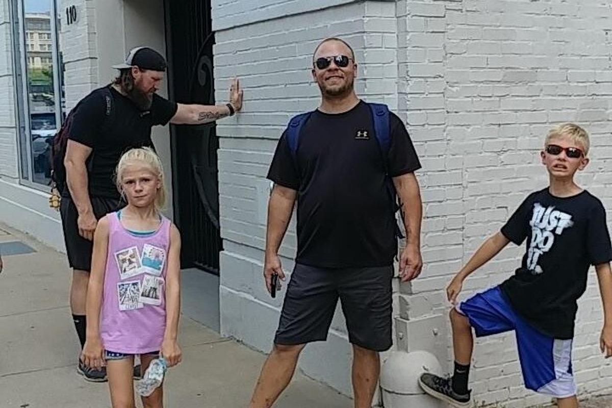 a man and two children standing next to a building