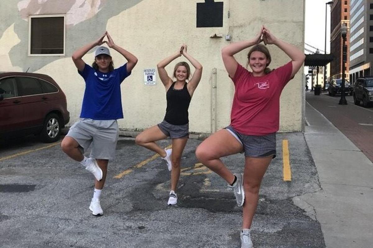 a group of three people doing yoga on a street