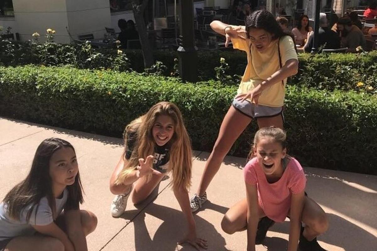a group of girls on a sidewalk with a woman