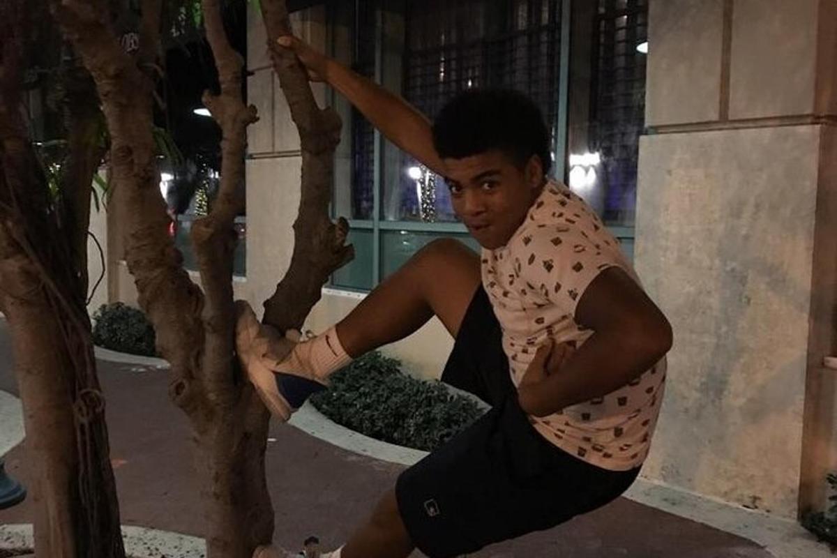 a young man is sitting next to a tree