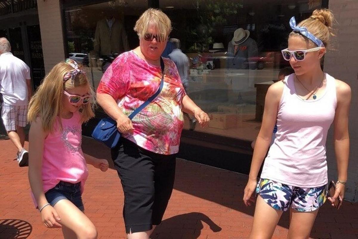a woman and two girls walking down a street