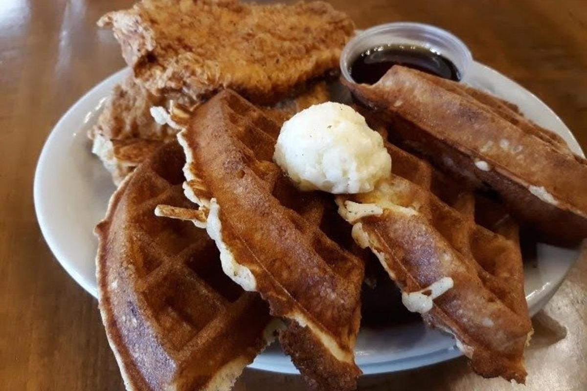 un piatto bianco con waffle e sciroppo su un tavolo