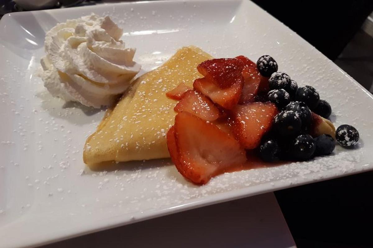 Un plato de postres con frutas y crema batida.