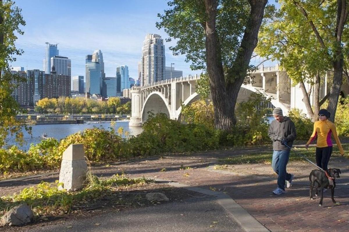 a man and a woman walking a dog near a bridge