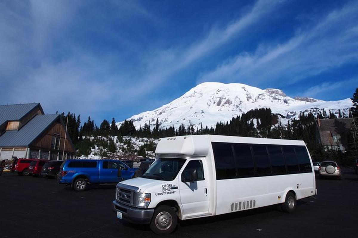 a white van parked in a parking lot with a snow covered mountain