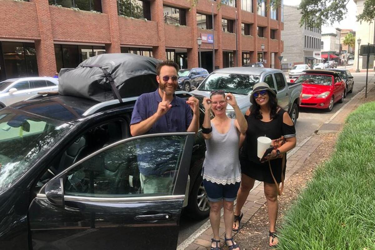a group of three people standing next to a car