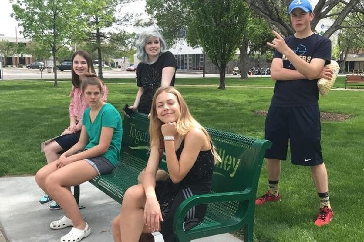 a group of people sitting on a bench in a park