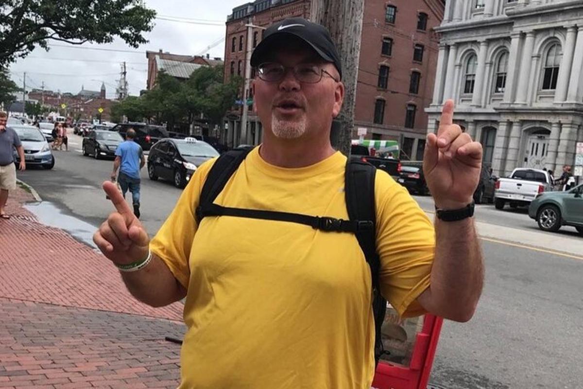 a man in a yellow shirt standing on a street