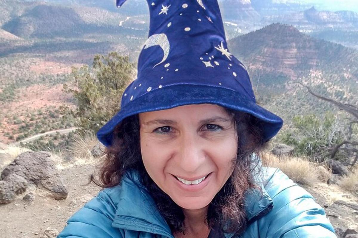 a woman wearing a witch hat on top of a mountain