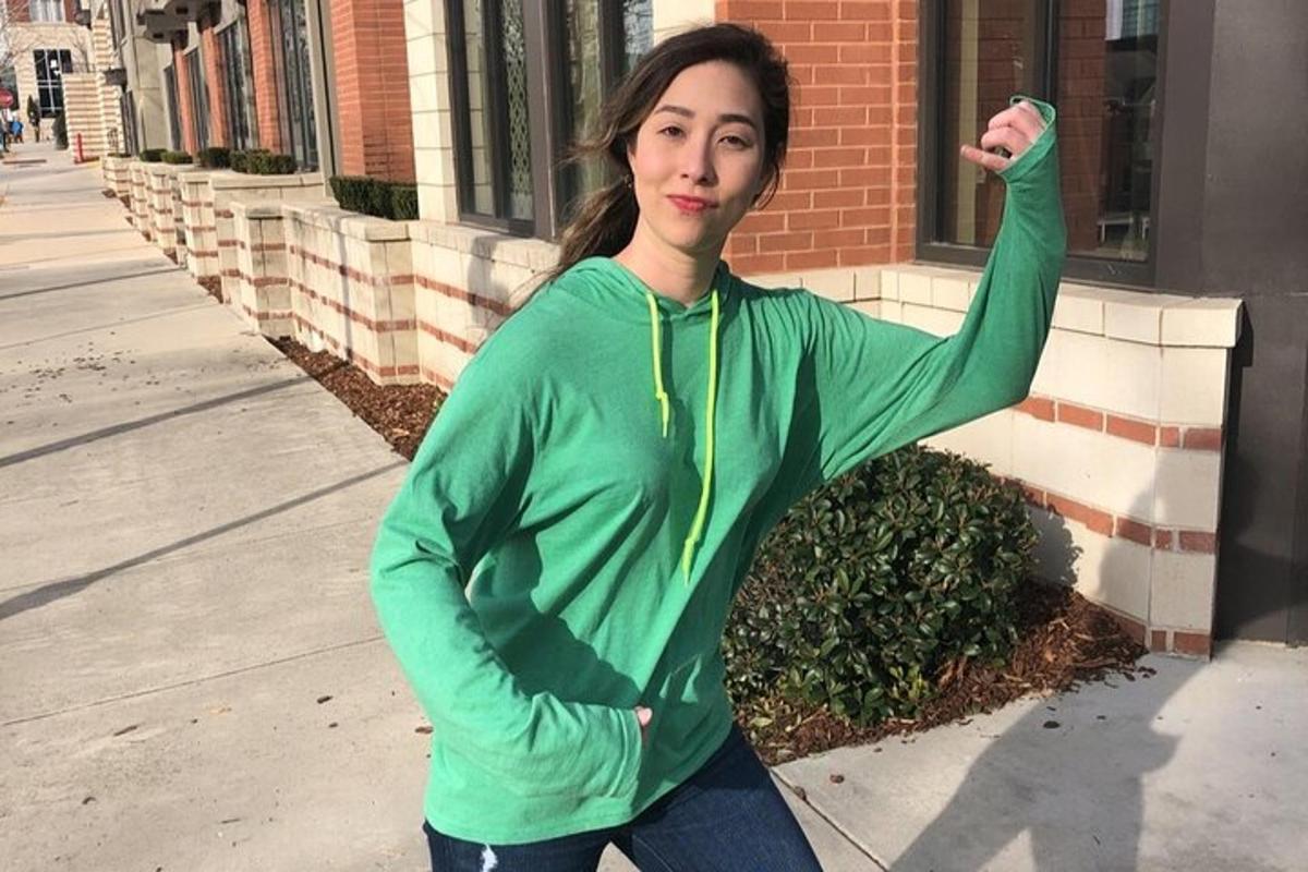 a woman in a green sweatshirt standing in front of a building