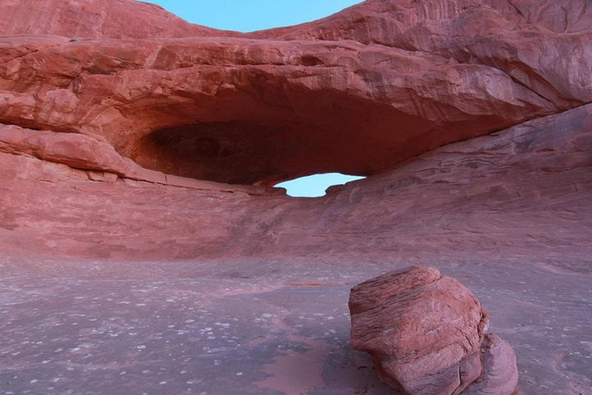 a cave in the desert with a rock in the water