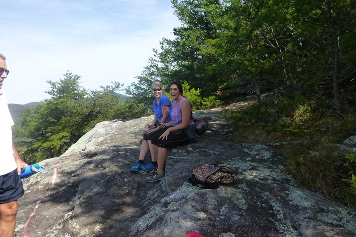 two women sitting on top of a rock with a turtle