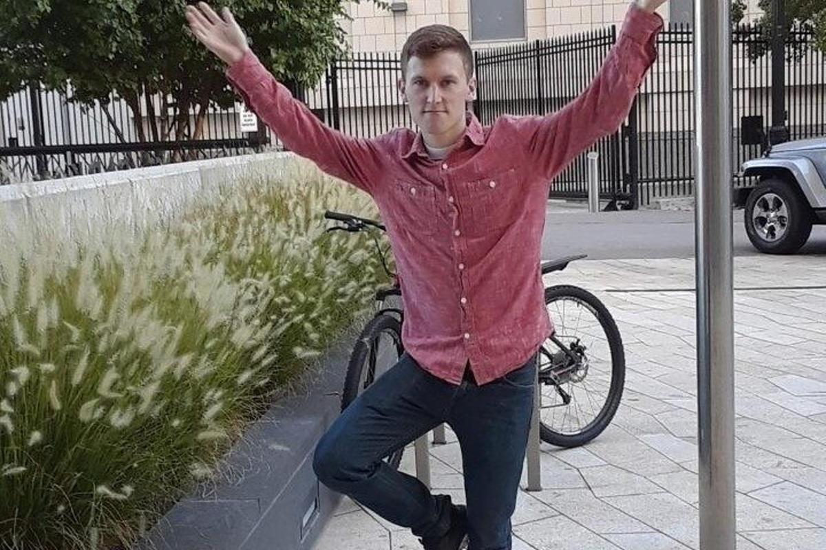 un bărbat care stă lângă o bicicletă cu brațele întinse