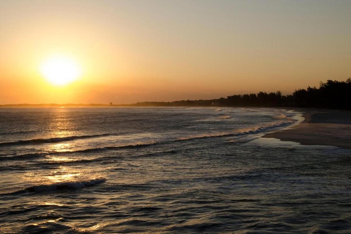 pantai dengan matahari terbenam di kejauhan