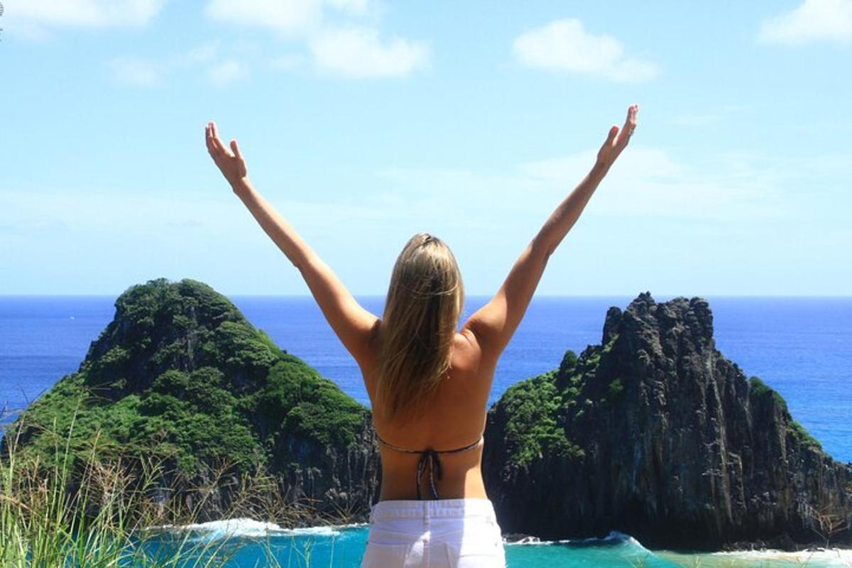 a woman standing on a beach with her arms in the air