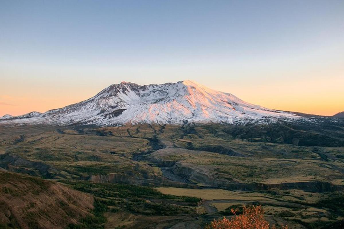 una montagna innevata con un tramonto sullo sfondo