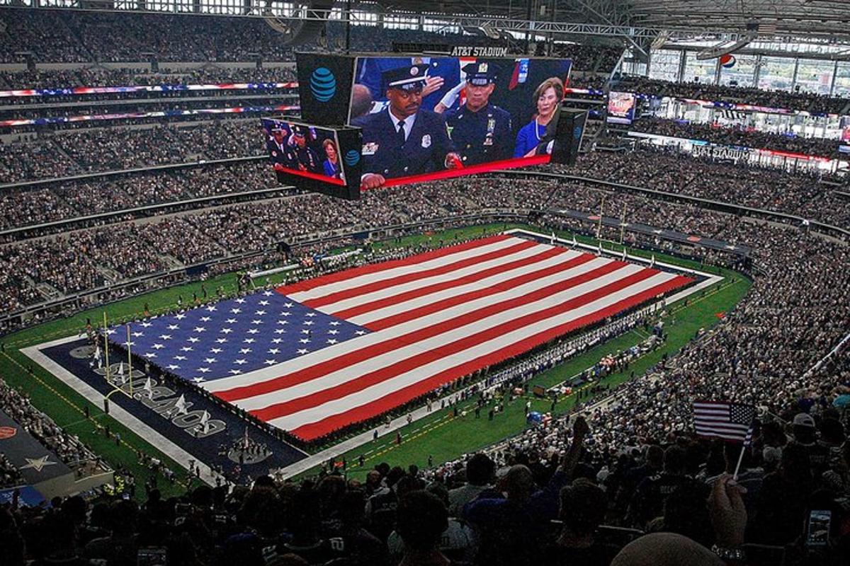 a large american flag in a stadium with a crowd