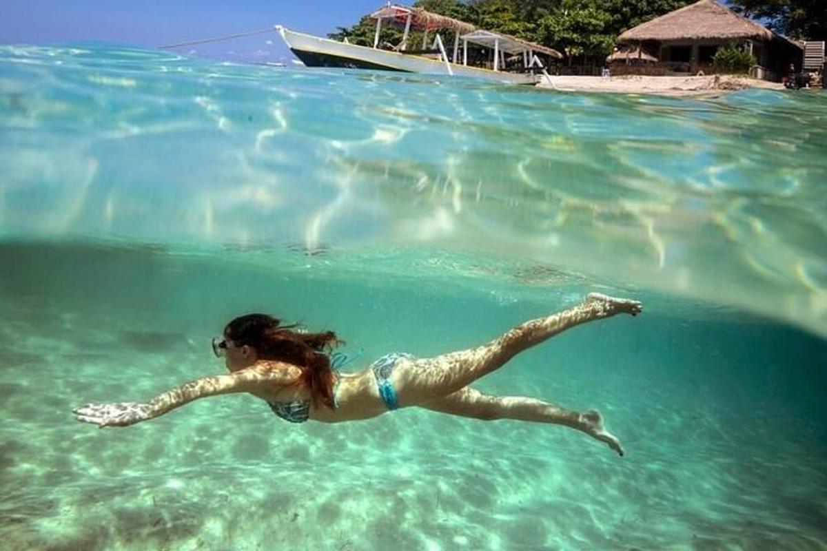 a woman swimming in the water with a boat