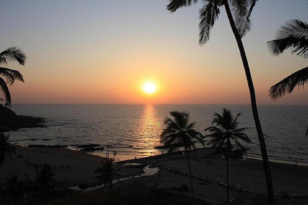 um pôr do sol sobre o oceano com palmeiras em uma praia
