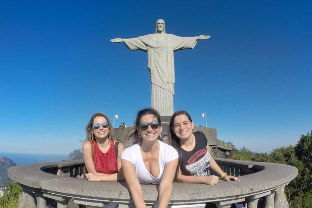 Tres niñas sentadas frente a una estatua del Cristo Redentor