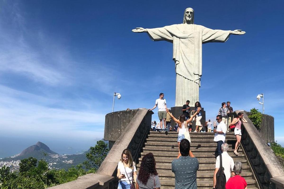 a group of people standing around a statue of christ the redeemer