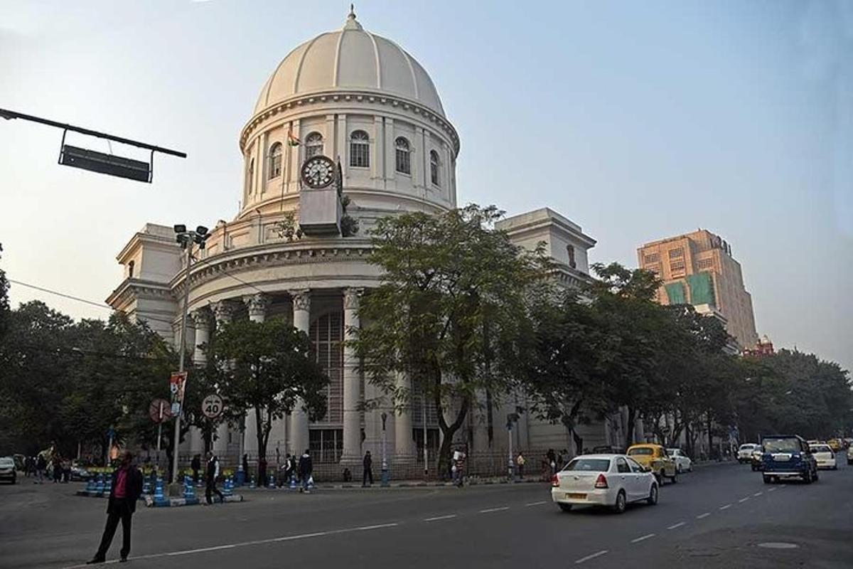 Un gran edificio blanco con una torre de reloj en una calle.