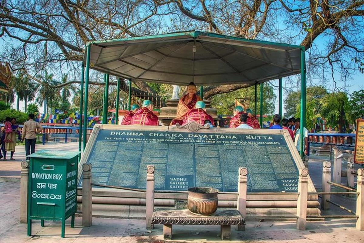 a sign in a park with people sitting under an umbrella