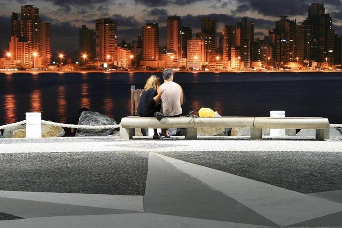 a man and a woman sitting on a bench near the water