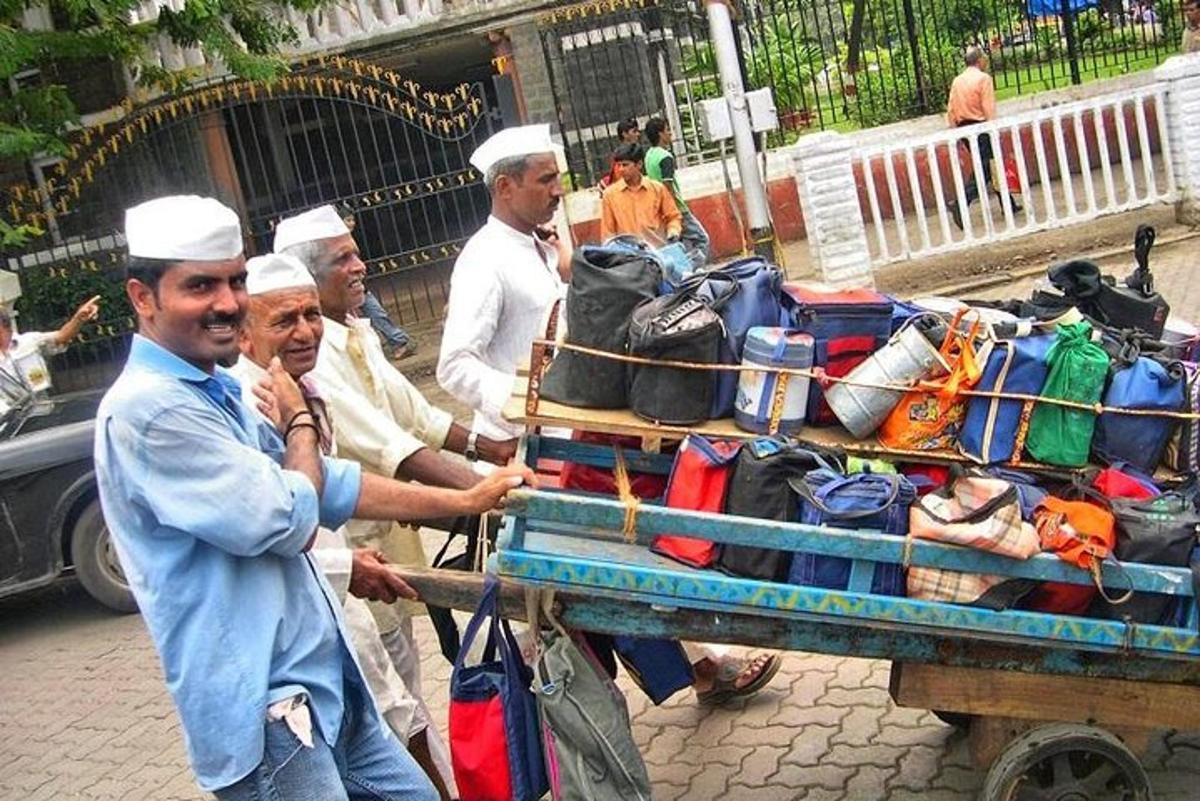 a group of men standing next to a cart with luggage