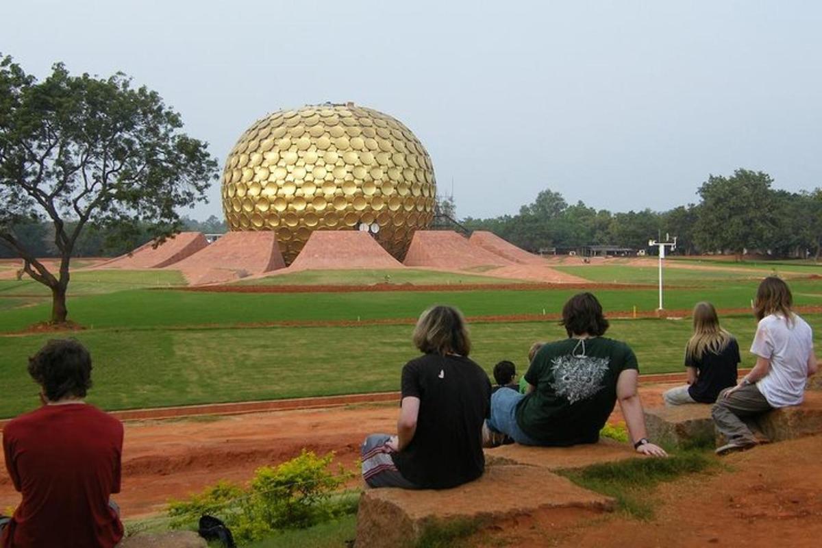 a group of people sitting on a rock looking at a large sphere