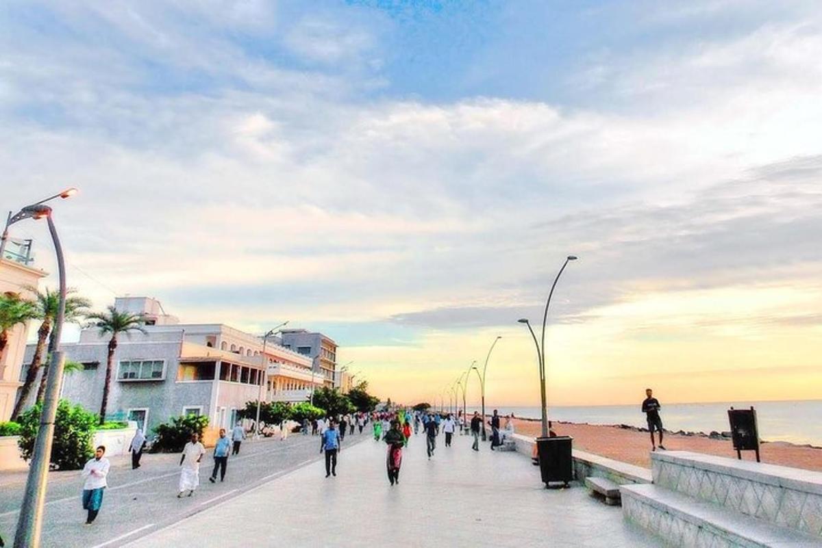 a group of people walking down a sidewalk near the beach