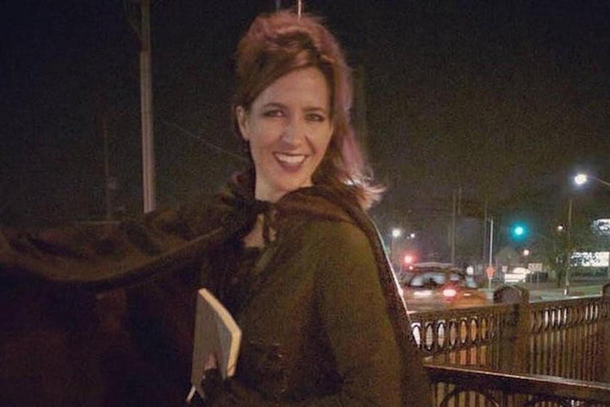 una donna sorride mentre tiene in mano un libro