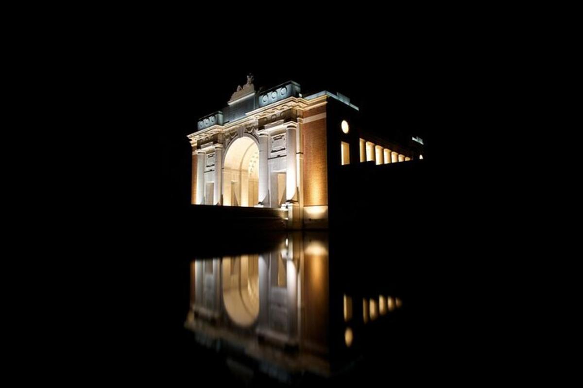 Un edificio con sus luces encendidas en el agua por la noche.