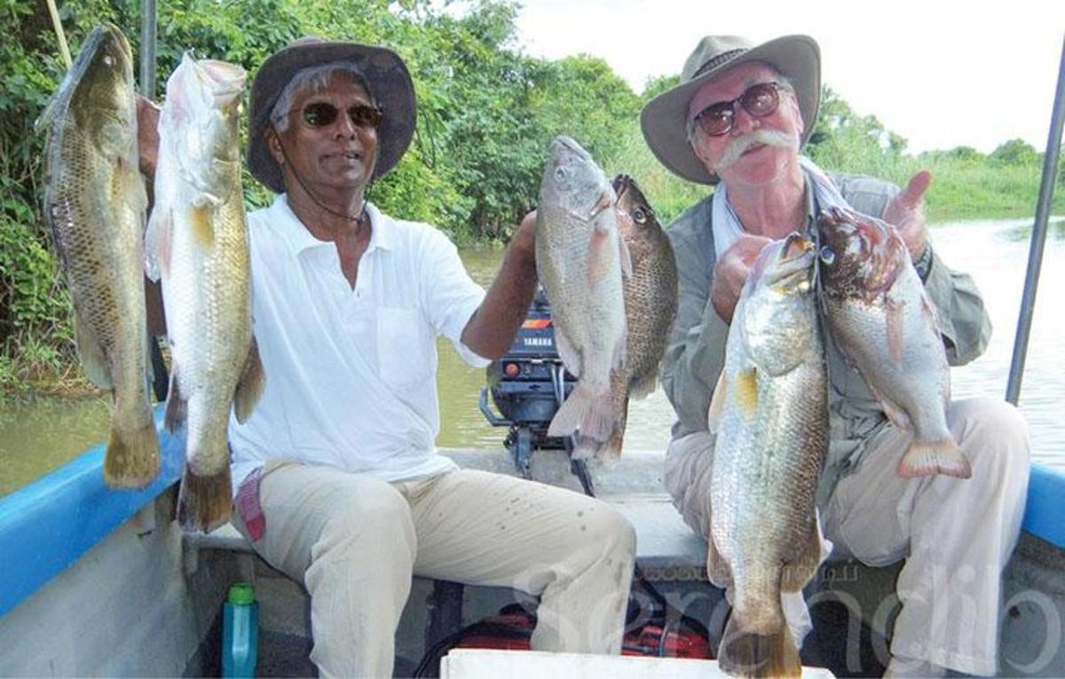 dois homens sentados em um barco segurando peixes