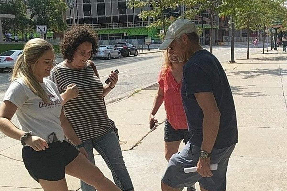 un grupo de personas caminando por una acera con un perro