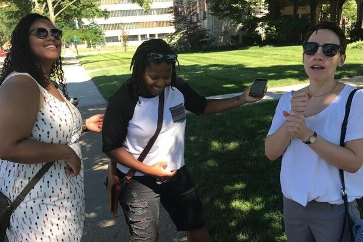 three women standing in a park with a cell phone