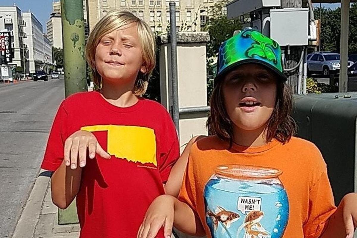 dva mladí chlapci sedící na rohu ulice s plechovkou