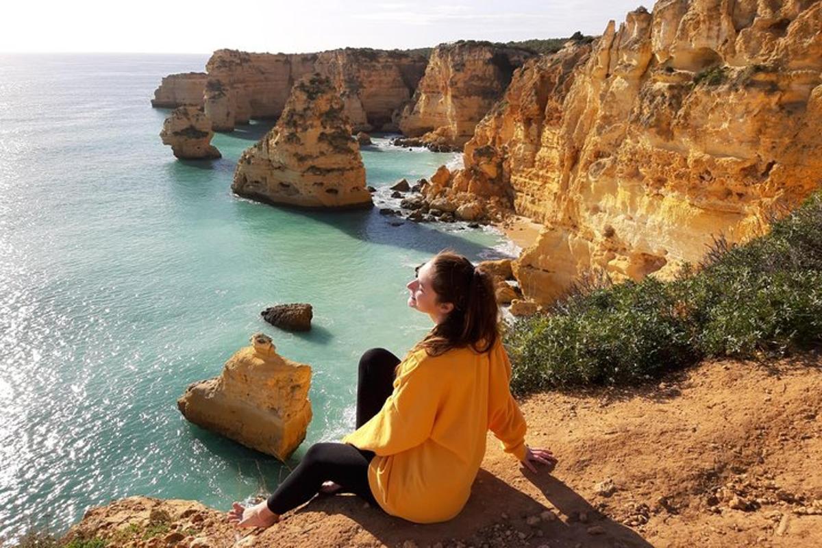una donna seduta su una scogliera che domina l'oceano