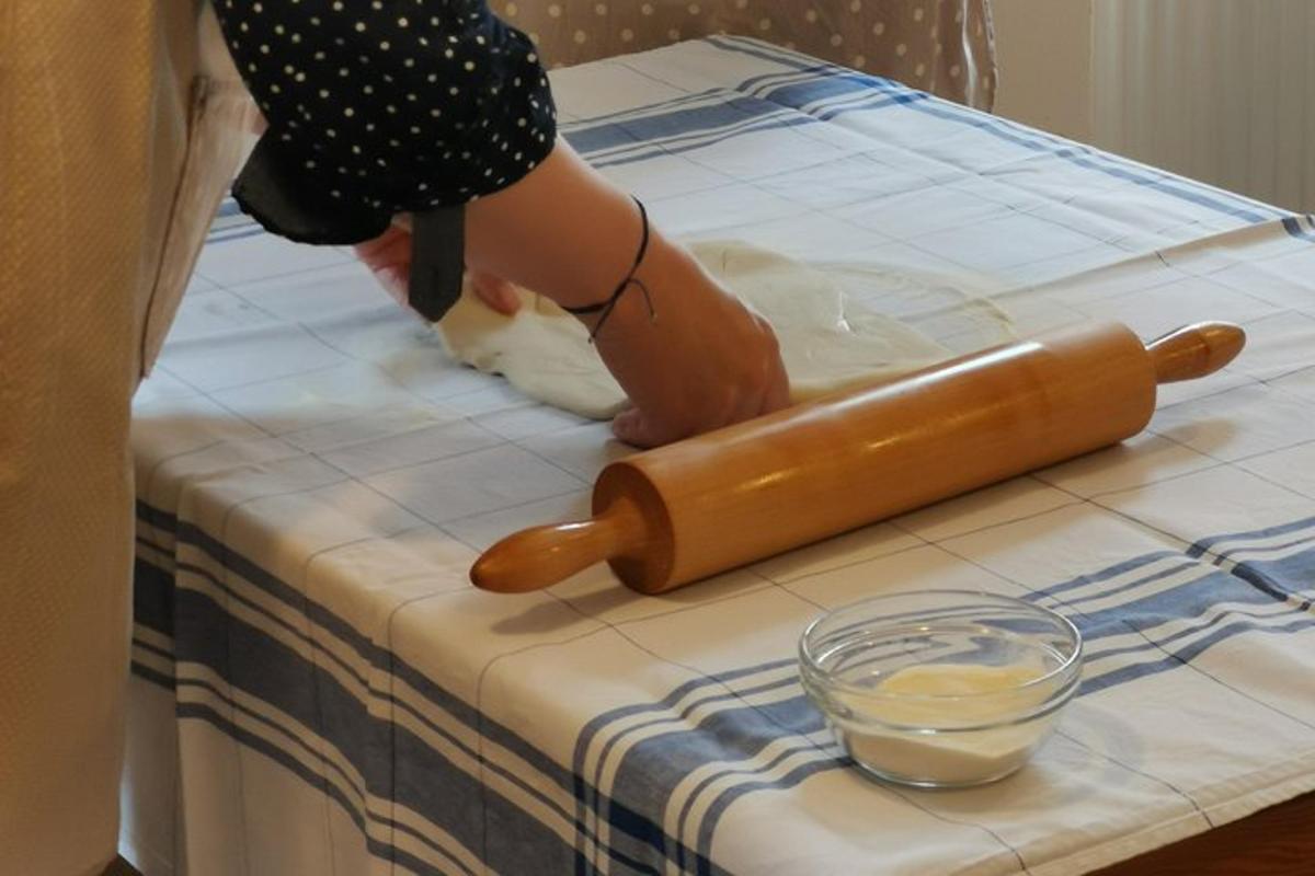 una dona talla una massa sobre una taula