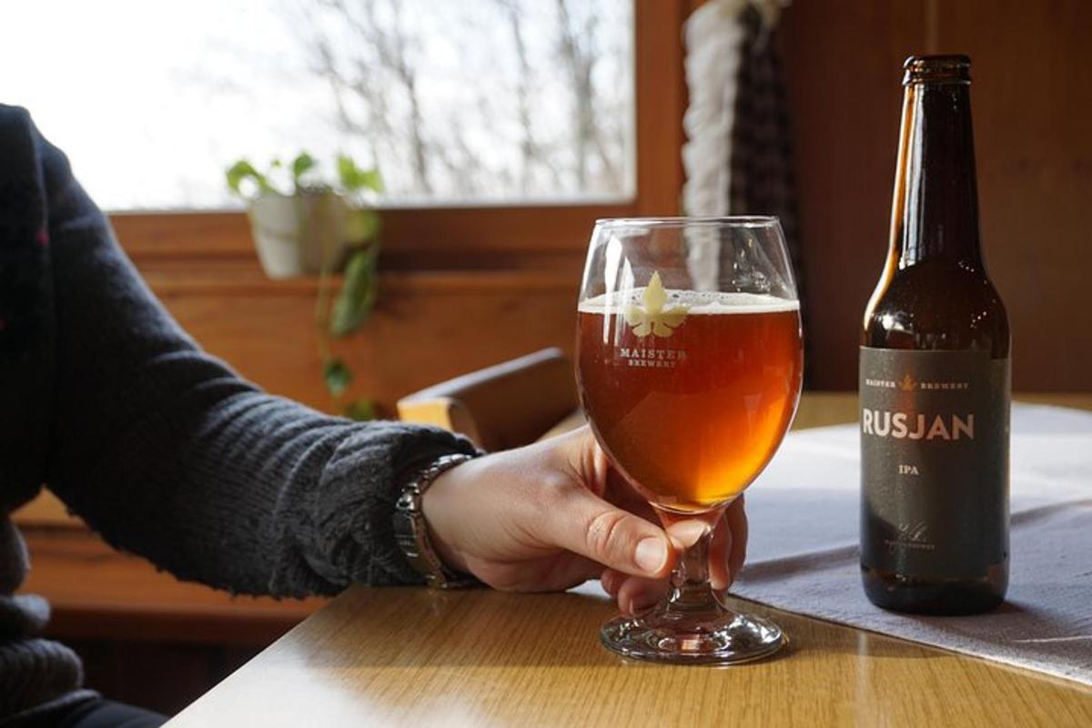 una persona que sosté un got de cervesa al costat d'una ampolla