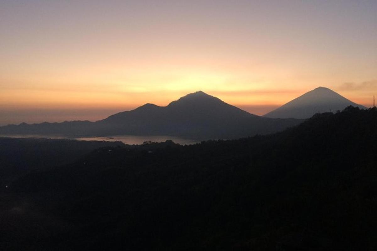 una silhouette di una montagna con un tramonto sullo sfondo