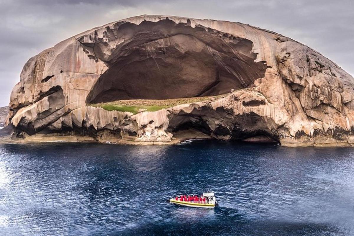 a boat in the water in front of a rock formation