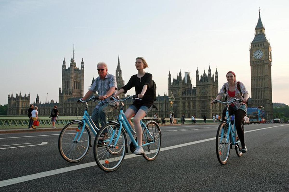 tiga orang mengendarai sepeda di jalan di depan Big Ben