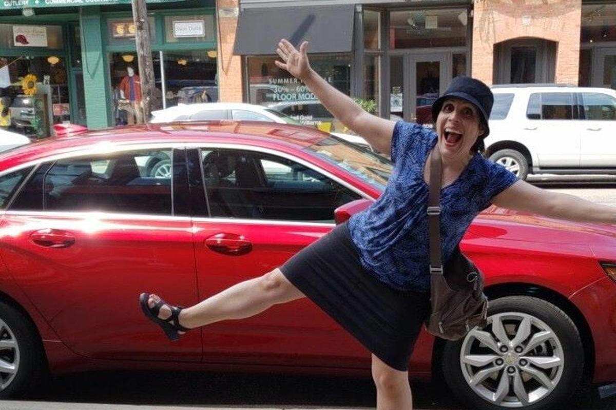 uma mulher está dançando na frente de um carro vermelho