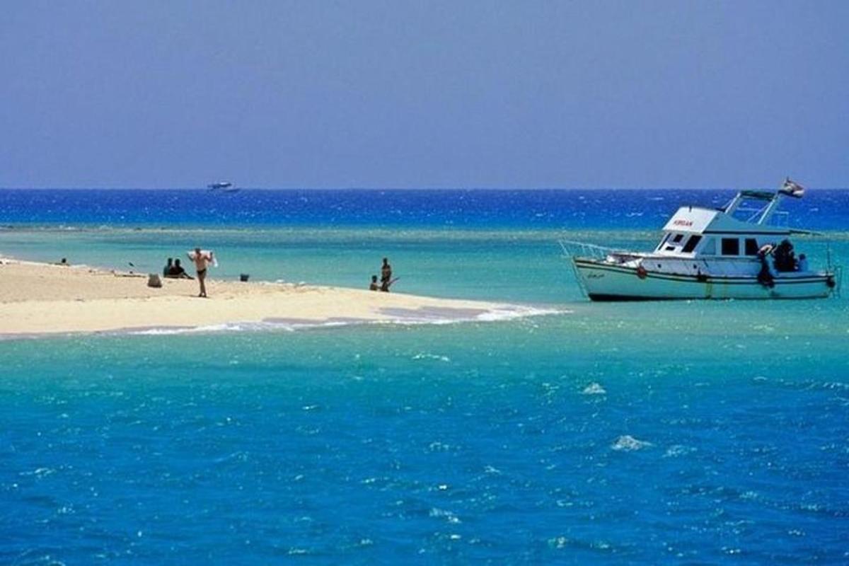 Un barco estacionado en una playa con gente a bordo.