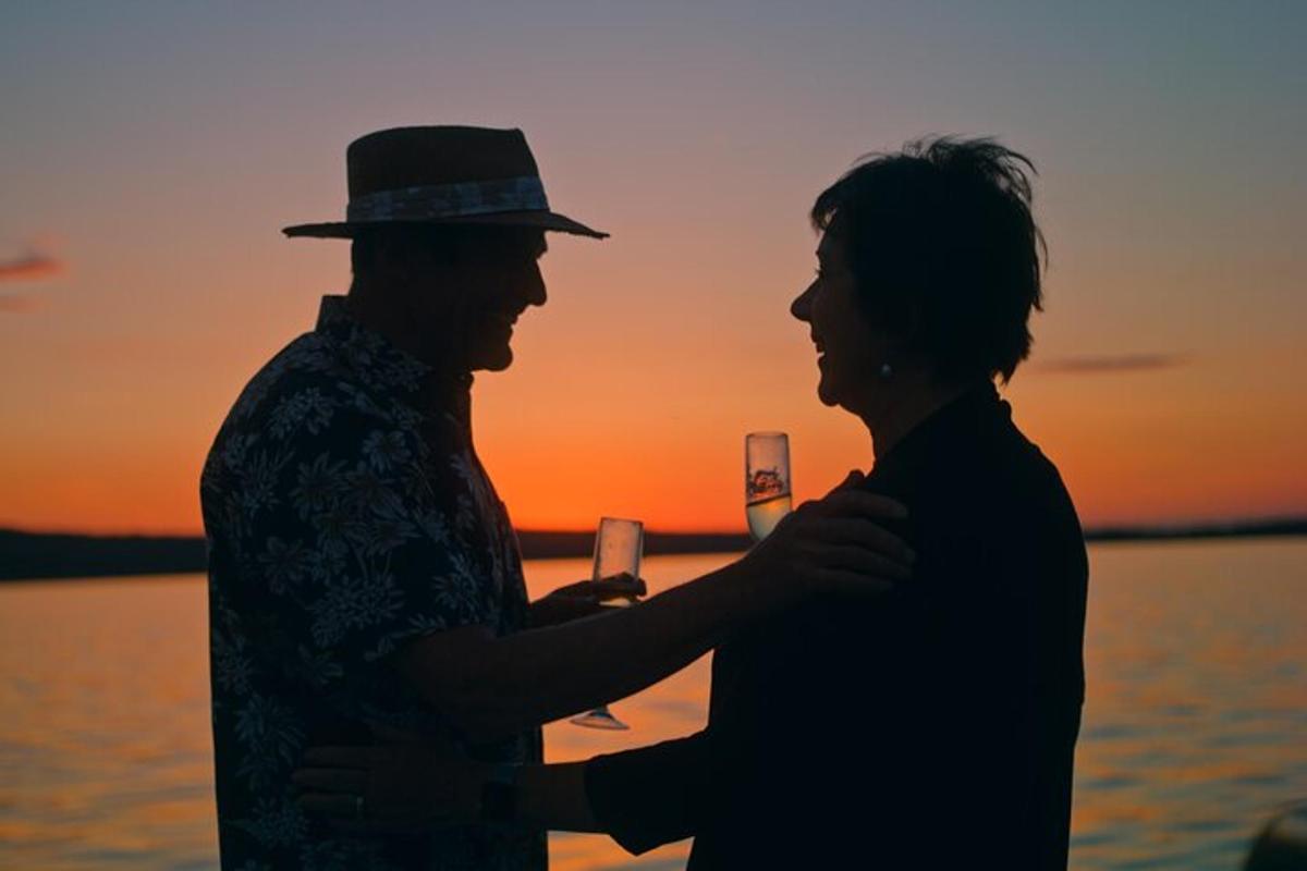 two people standing next to each other with a glass of wine