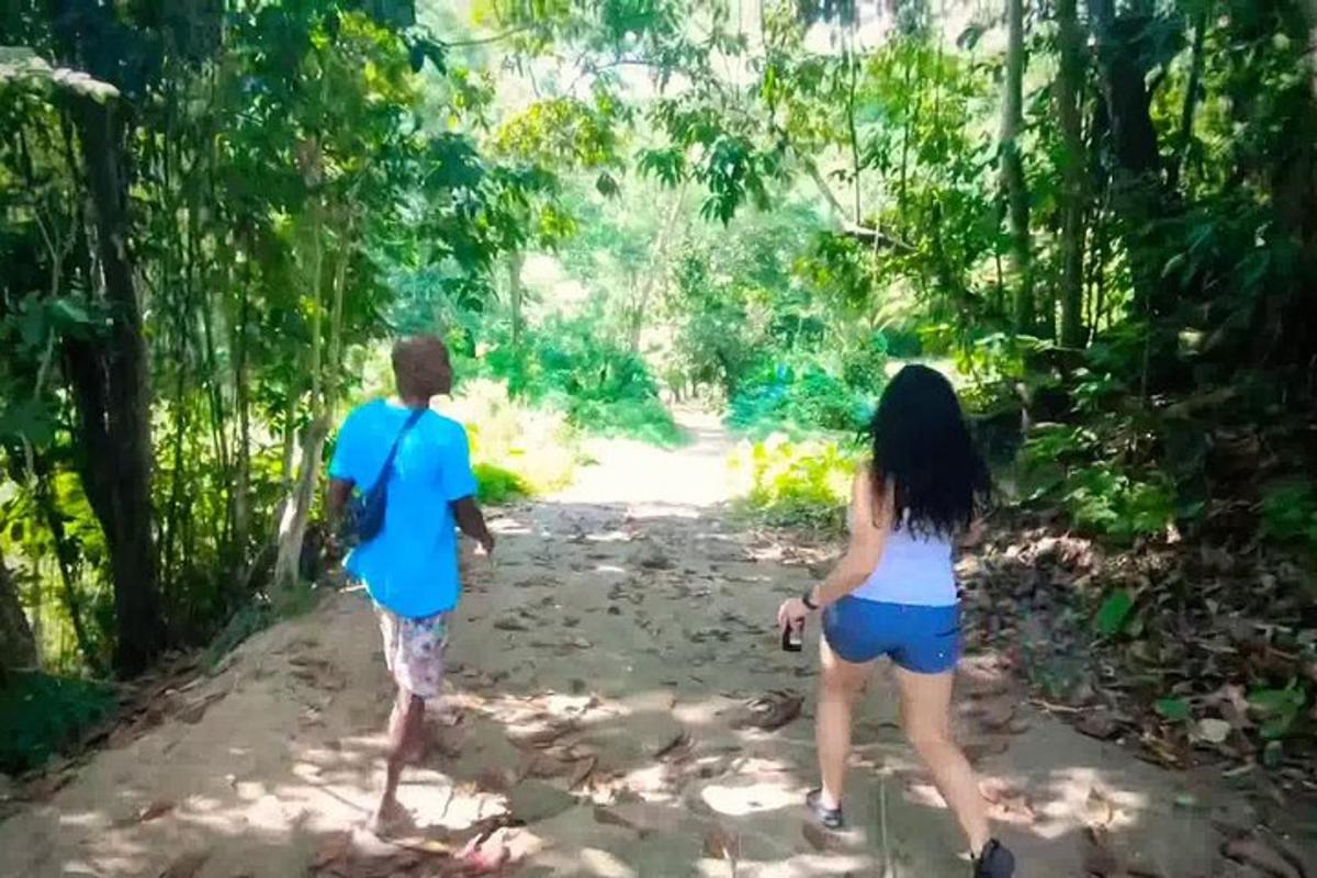 Dos personas caminando por un sendero de tierra en el bosque.