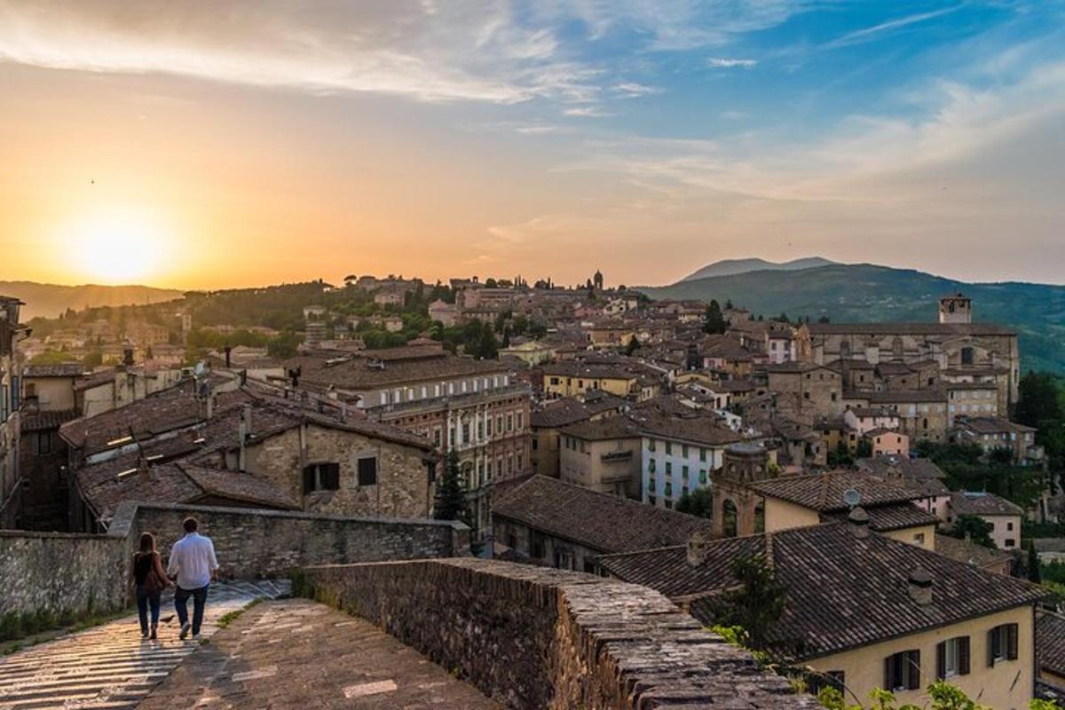 two people walking down a stone wall looking over a city